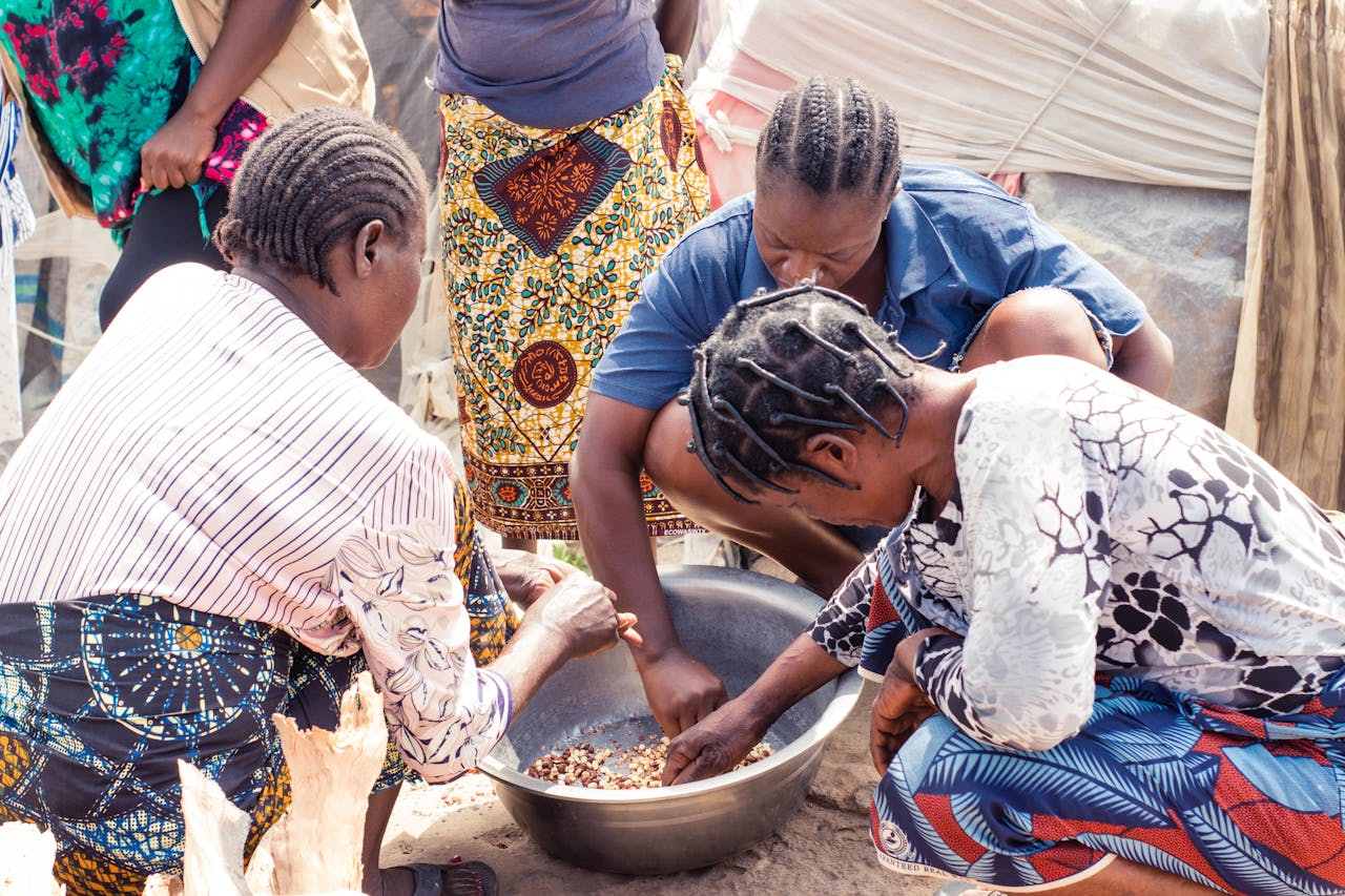 hero-img-01 Group of women collaboratively sorting beans outdoors, showcasing cultural richness.