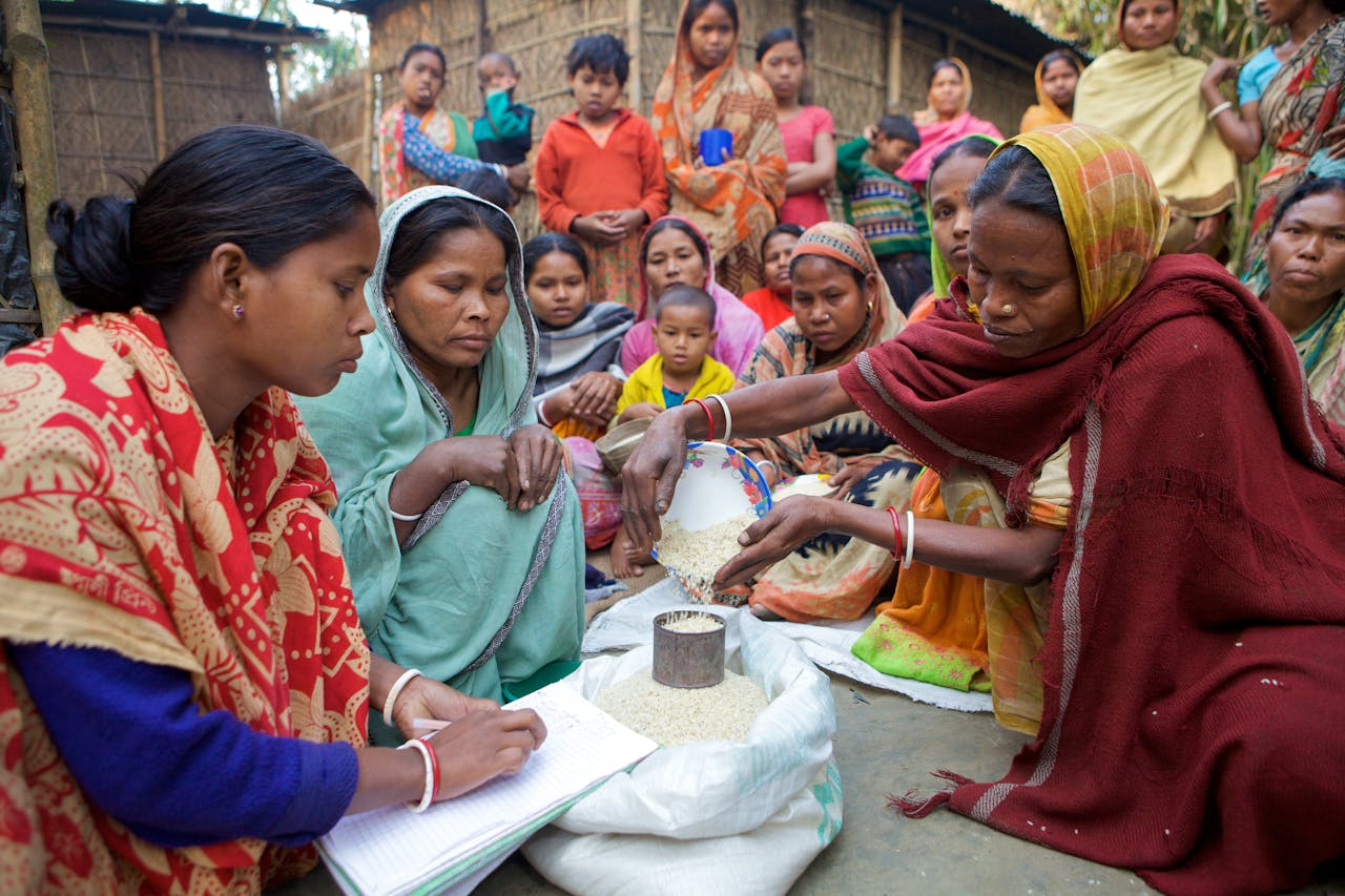 hero-img-02 Village women in Bangladesh gather for community development planning and resource distribution.